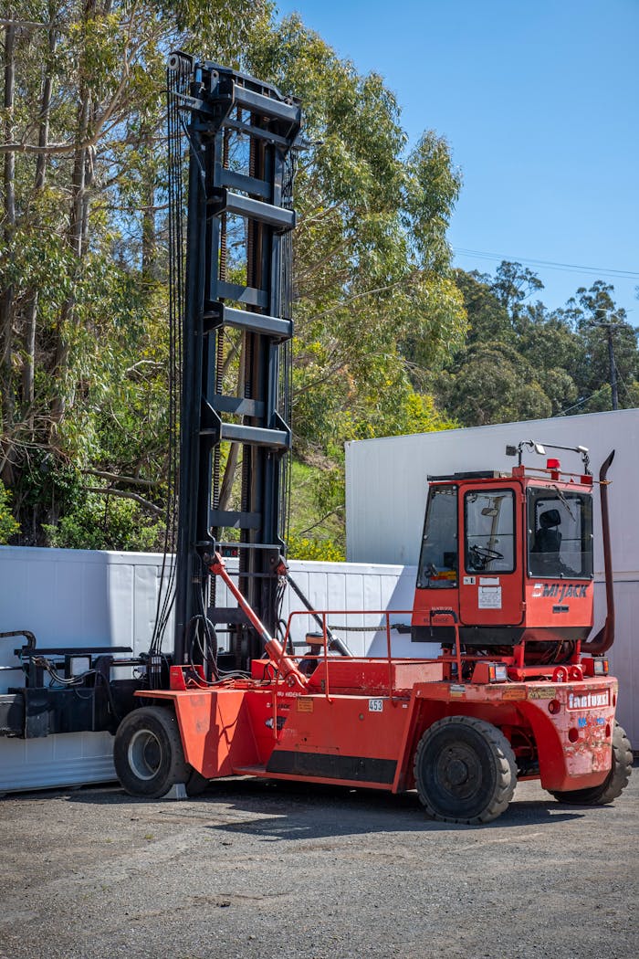 A large red forklift with extended lifting mechanism parked outdoors.